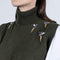 Woman wearing a green knit vest with embroidered designs on a white background