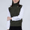 Woman wearing a green knitted vest over a white shirt on a plain background